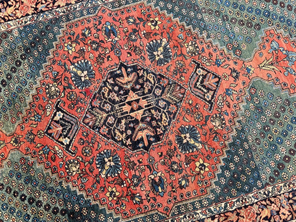 An antique hand-knotted Bakhtiar wool rug featuring a central terracotta stepped medallion on a dark indigo field filled with intricate floral motifs. View XI