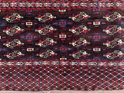 fig 1. Handwoven antique Turkmen Yomut chuval featuring repeating tribal gul motifs in deep red and brown tones with a patterned lower elem and braided top handles.