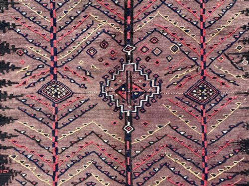 fig 2. A square antique handwoven Ru Korsi textile featuring a dusty purple central field with chevron tree motifs bordered by dark geometric band patterns.