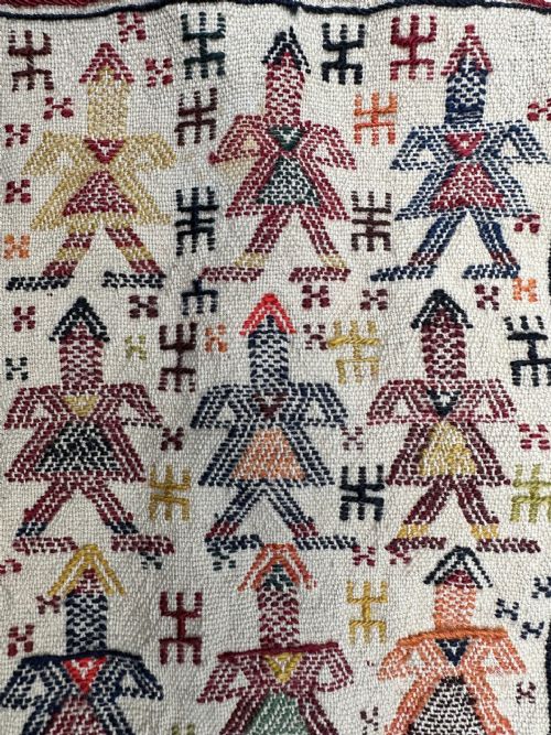 fig 1. A handwoven antique Persian Qashqai bag decorated with anthropomorphic figures, framed by geometric borders and long multi-coloured tassels.