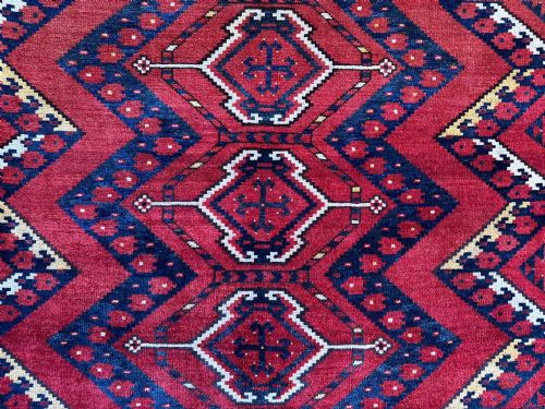 fig 1. A rectangular hand-knotted wool Turkmen storage bagface featuring central diamond motifs woven in crimson red, dark navy blue, yellow, and cream with fringed edges.