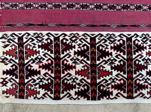 fig 1. An antique Turkmen Ak Chuval textile featuring horizontal burgundy and black geometric bands above an ivory bottom panel with tree motifs.
