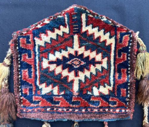 fig 1. A pair of pentagonal hand-woven wool Turkmen dizlyks featuring red and blue geometric patterns with hanging wool tassels.
