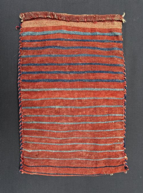 fig 1. A rectangular hand-woven tribal wool bag face with geometric diamond motifs in terracotta red, indigo blue, and cream.