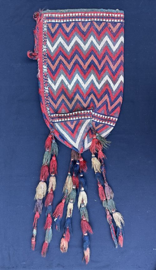 fig 1. An antique hand-woven Turkmen Uk Bash tent pole cover featuring red and blue chevron patterns with long braided wool tassels hanging below.