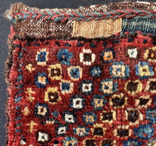 fig 1. An antique handwoven Luri vanity bag with a dense geometric square pattern in red, blue, yellow, and white wool.