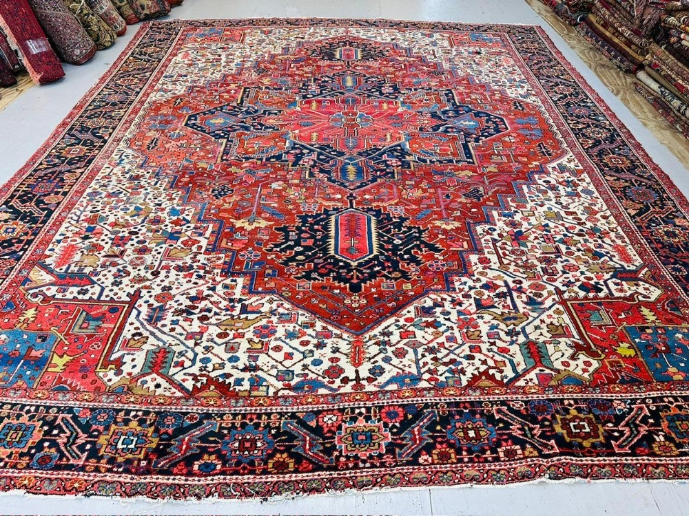 An antique Heriz carpet featuring a large central geometric medallion pattern in red, blue, and cream.
