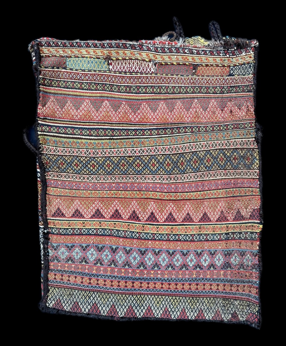An antique rectangular handwoven Qashqai tribal storage bag featuring horizontal bands of fine geometric, chevron, and diamond patterns in terracotta red, dark blue, and yellow wool.