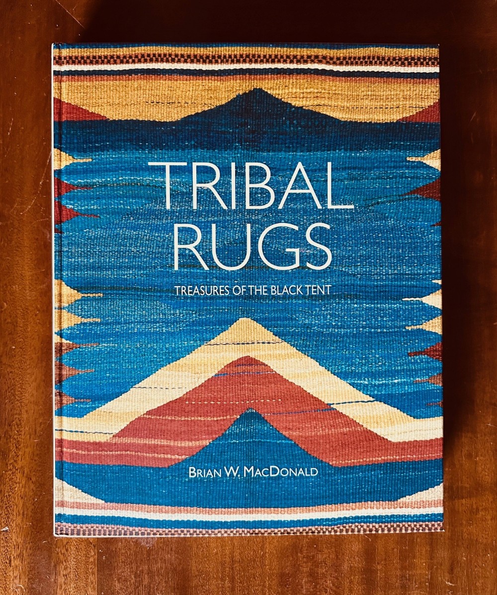 A hardcover reference book titled Tribal Rugs: Treasures of the Black Tent by Brian W. MacDonald with a woven geometric pattern cover.