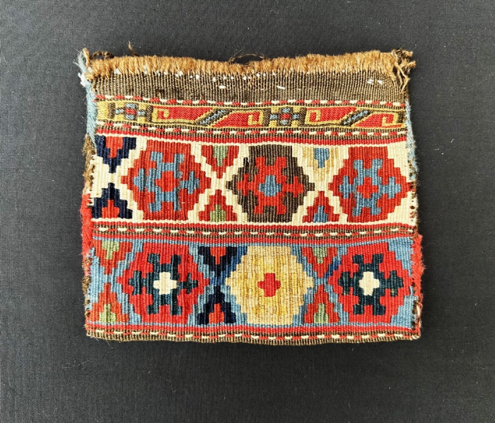 An antique Shahsevan hand-woven wool pouch featuring geometric hexagonal motifs in red, cream, blue, and yellow.