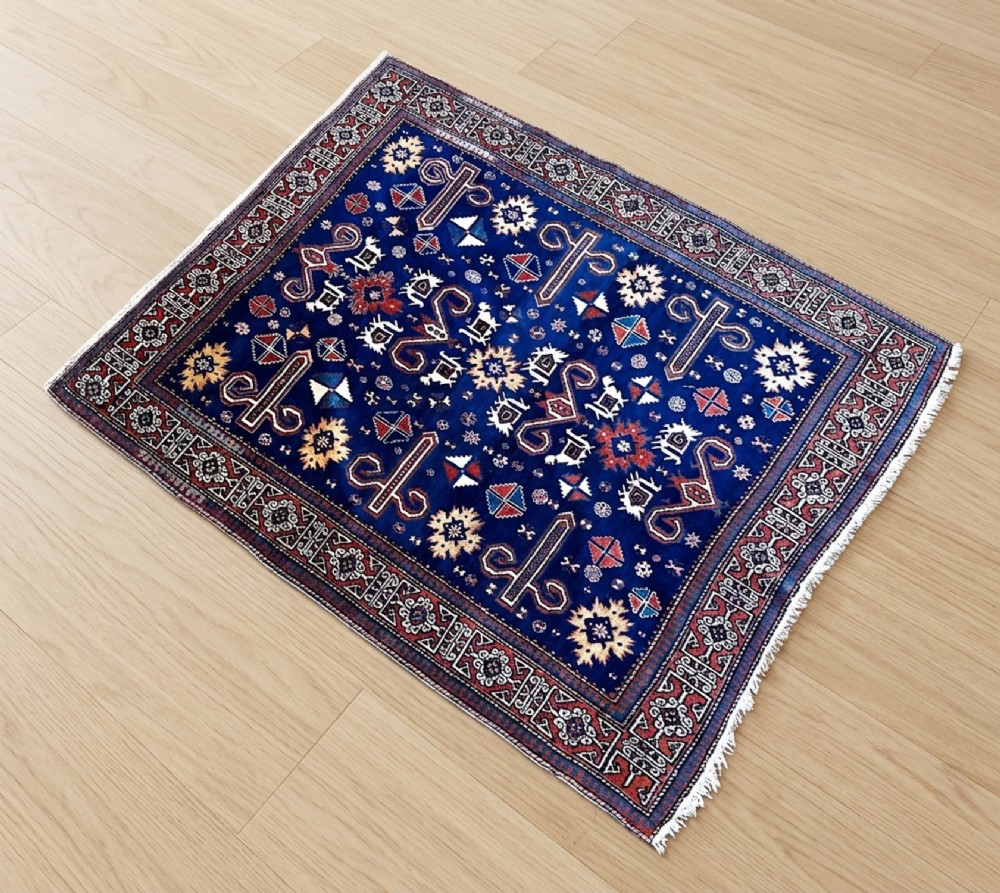 An antique Caucasian Erivan rug featuring a deep indigo blue field filled with geometric rosettes, star motifs, and stylized animal figures within a multi-tiered rust red and ivory border.
