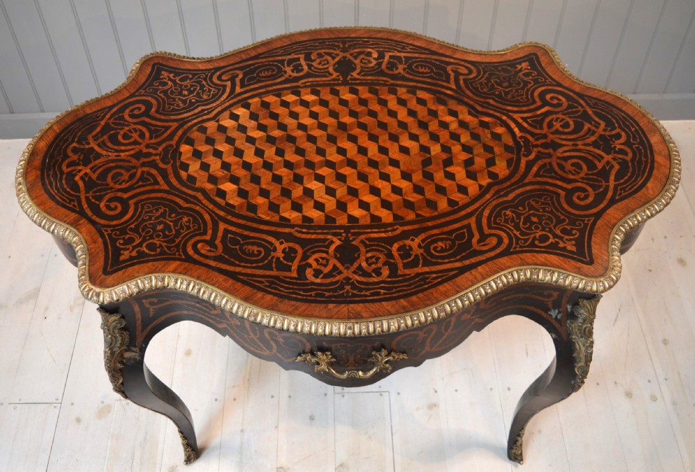 A French Louis XV style centre table featuring geometric cubed parquetry, scroll marquetry, a serpentine top, and decorative brass mounts.