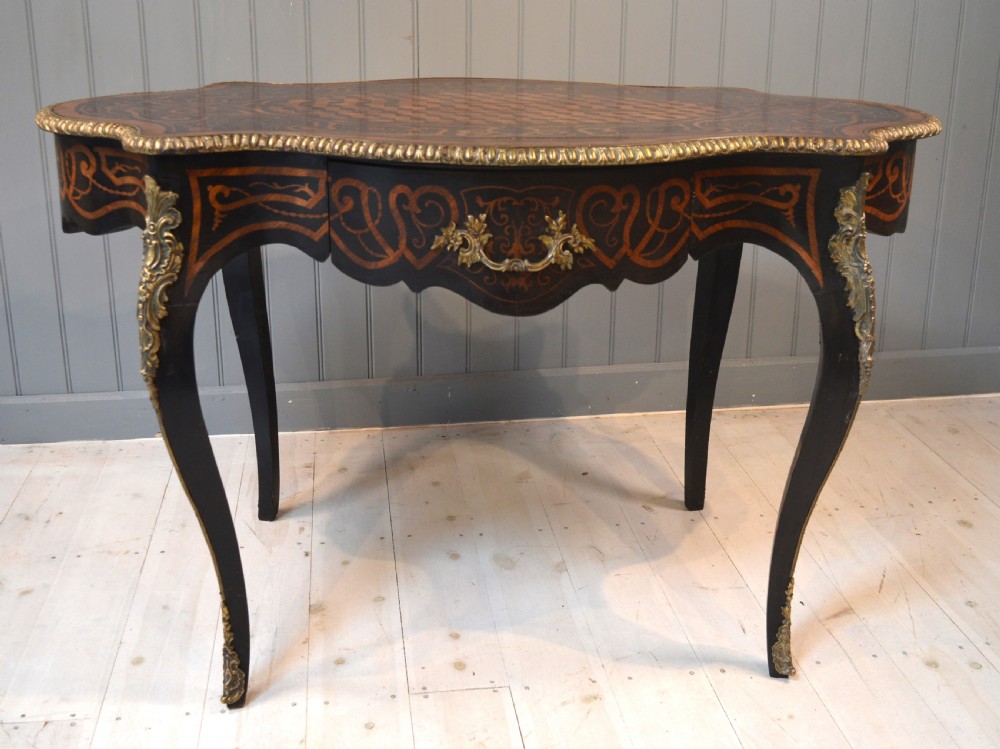 A French Louis XV style centre table featuring geometric cubed parquetry, scroll marquetry, a serpentine top, and decorative brass mounts. View II