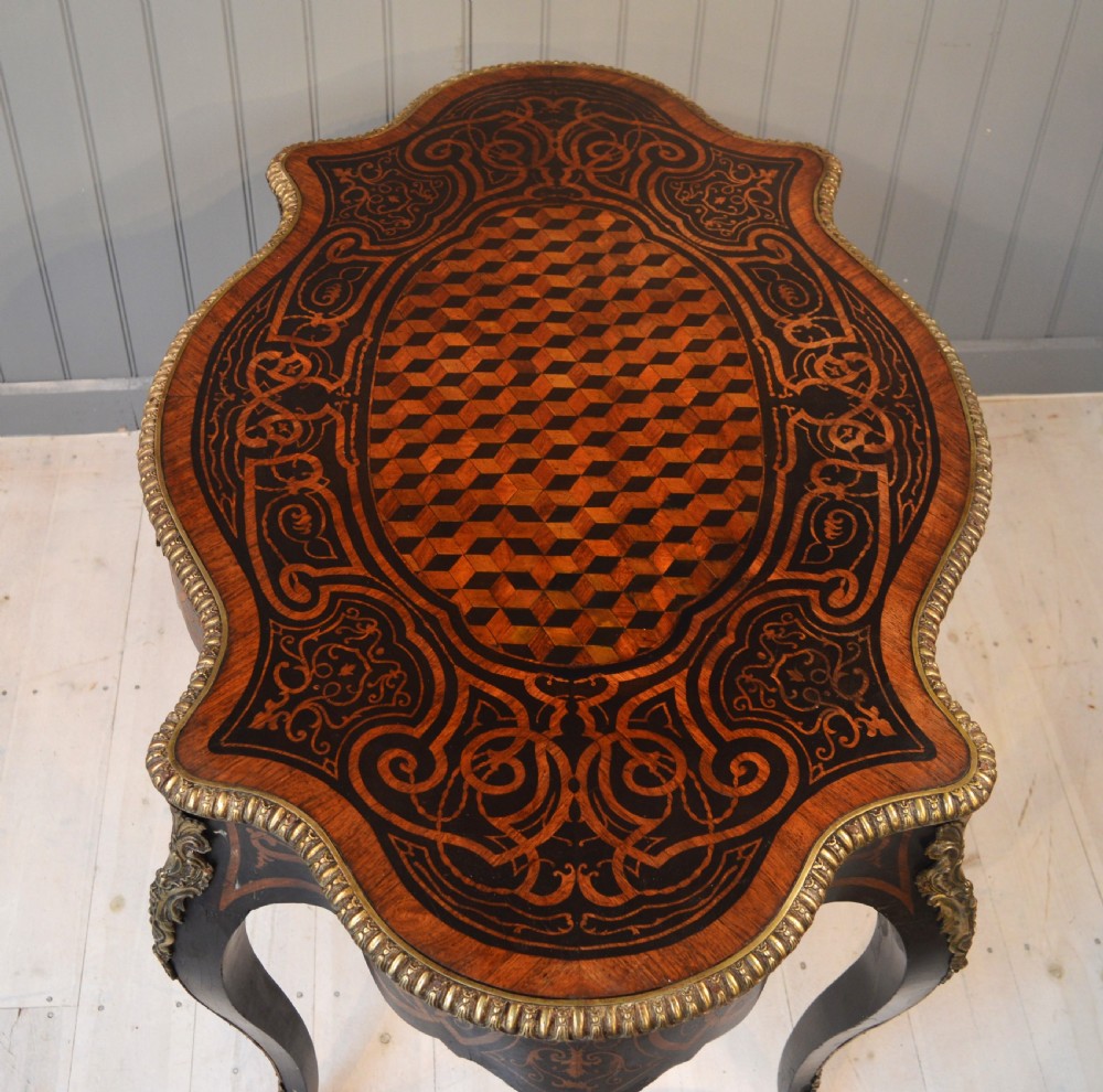 A French Louis XV style centre table featuring geometric cubed parquetry, scroll marquetry, a serpentine top, and decorative brass mounts. View III