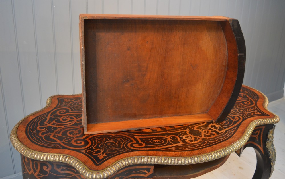 A French Louis XV style centre table featuring geometric cubed parquetry, scroll marquetry, a serpentine top, and decorative brass mounts. View V