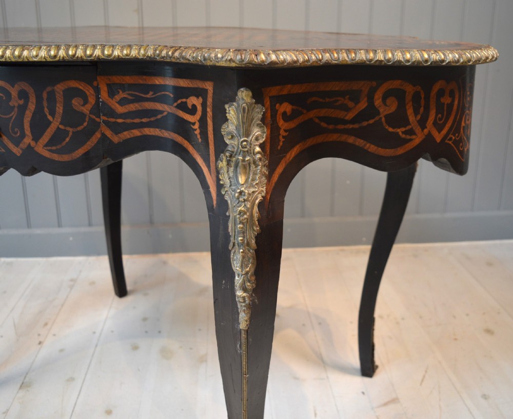 A French Louis XV style centre table featuring geometric cubed parquetry, scroll marquetry, a serpentine top, and decorative brass mounts. View VI
