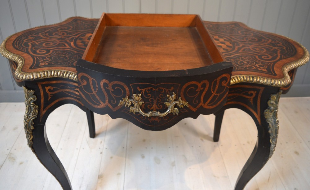 A French Louis XV style centre table featuring geometric cubed parquetry, scroll marquetry, a serpentine top, and decorative brass mounts. View VII