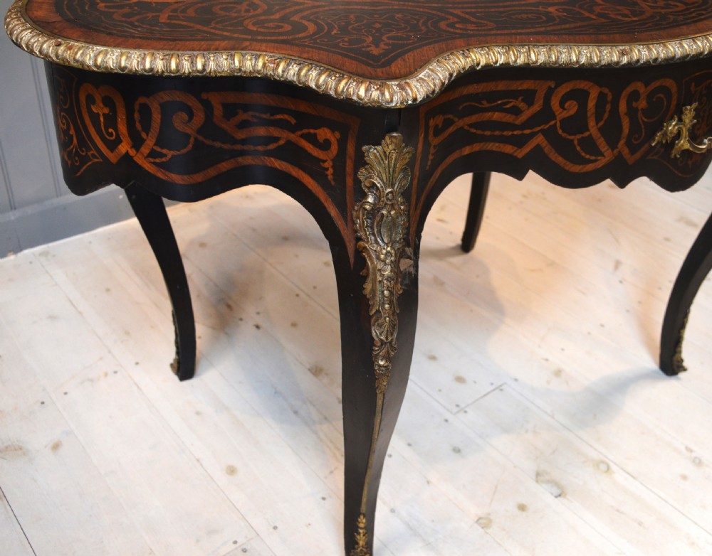 A French Louis XV style centre table featuring geometric cubed parquetry, scroll marquetry, a serpentine top, and decorative brass mounts. View IX