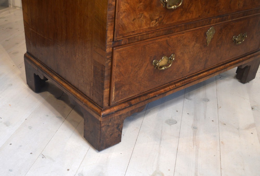 A burr walnut slant-front bureau featuring brass drop handles, keyhole escutcheons, and a lower chest of drawers set on bracket feet. View VIII