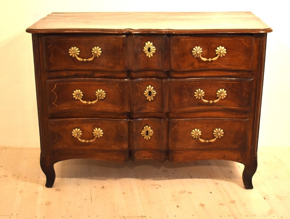 A French provincial walnut commode with three long drawers featuring brass rosette drop handles, keyhole escutcheons, and curved legs. View II