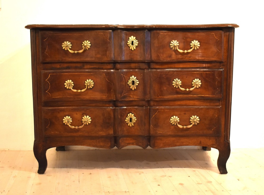 A French provincial walnut commode with three long drawers featuring brass rosette drop handles, keyhole escutcheons, and curved legs. View III