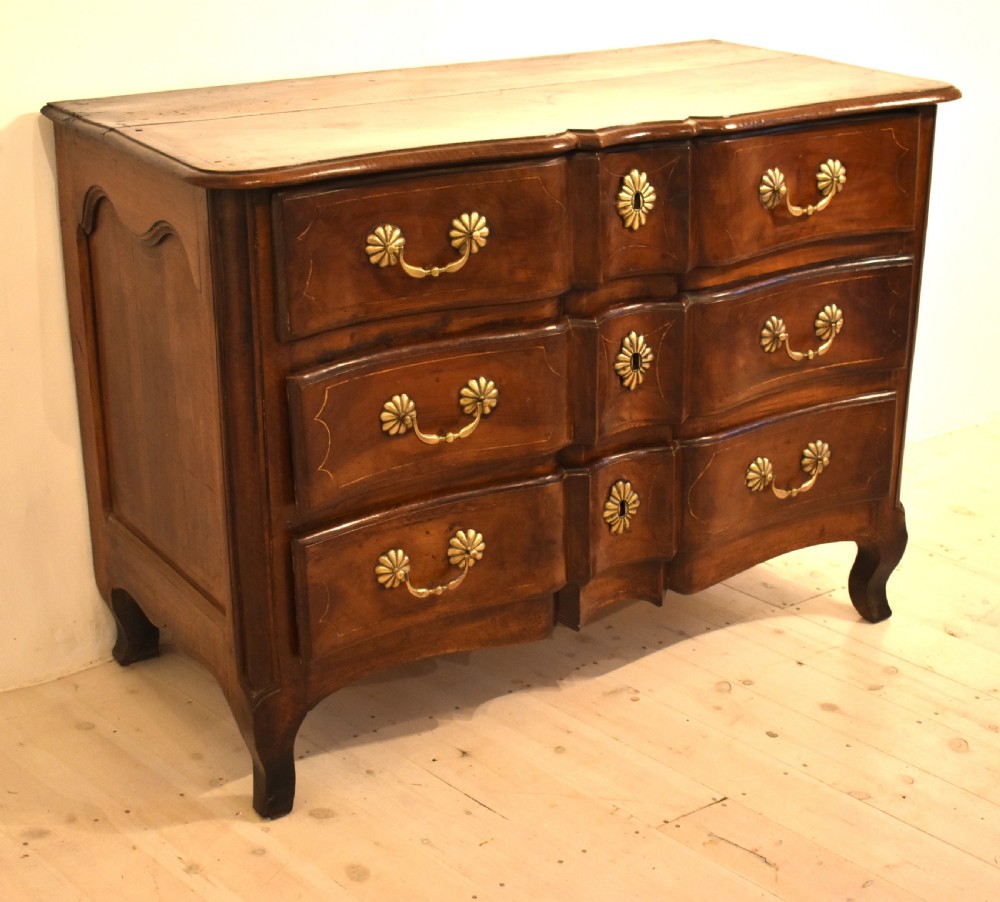 A French provincial walnut commode with three long drawers featuring brass rosette drop handles, keyhole escutcheons, and curved legs. View V