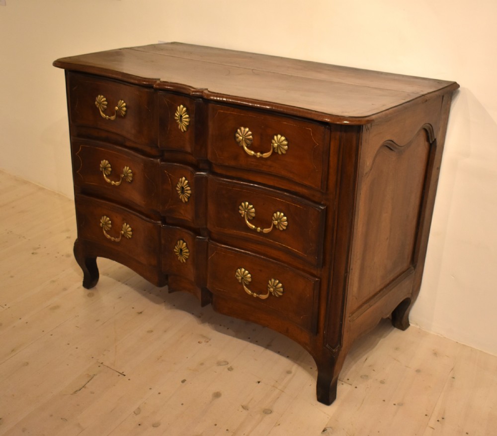 A French provincial walnut commode with three long drawers featuring brass rosette drop handles, keyhole escutcheons, and curved legs. View VI