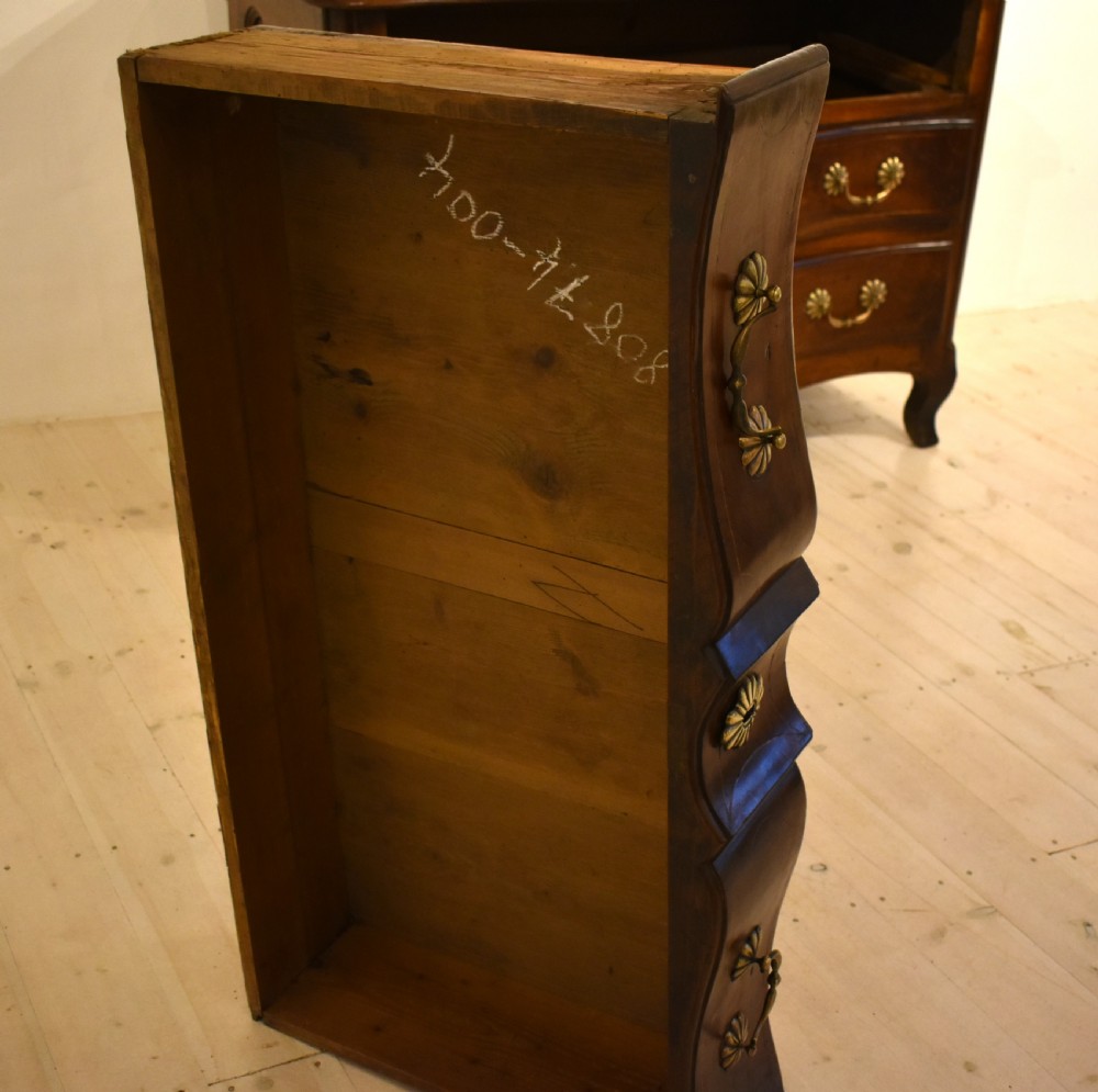 A French provincial walnut commode with three long drawers featuring brass rosette drop handles, keyhole escutcheons, and curved legs. View VII