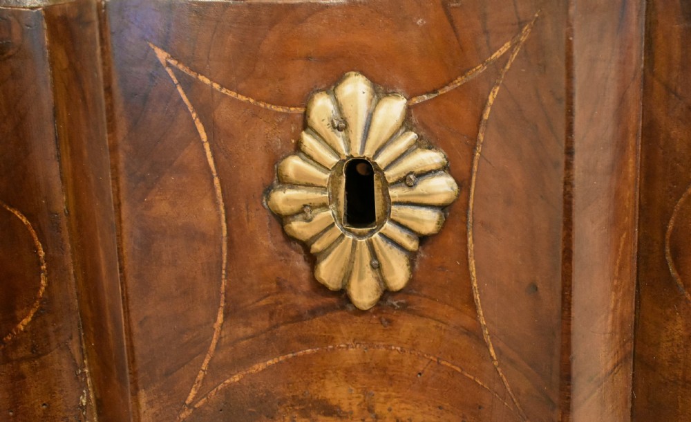 A French provincial walnut commode with three long drawers featuring brass rosette drop handles, keyhole escutcheons, and curved legs. View IX