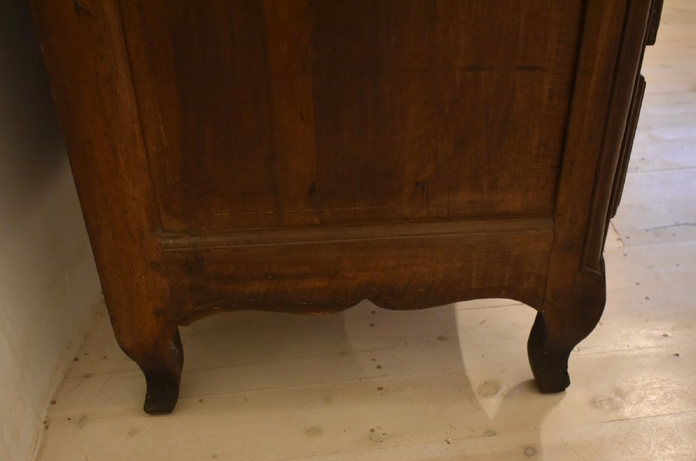 A French provincial walnut commode with three long drawers featuring brass rosette drop handles, keyhole escutcheons, and curved legs. View X