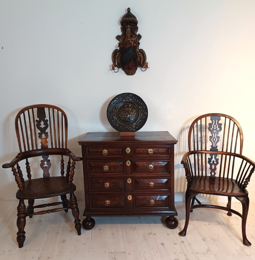 A 17th-century walnut chest of drawers with four moulded drawer fronts, brass drop handles, brass keyhole escutcheons, and large turned bun feet. View III