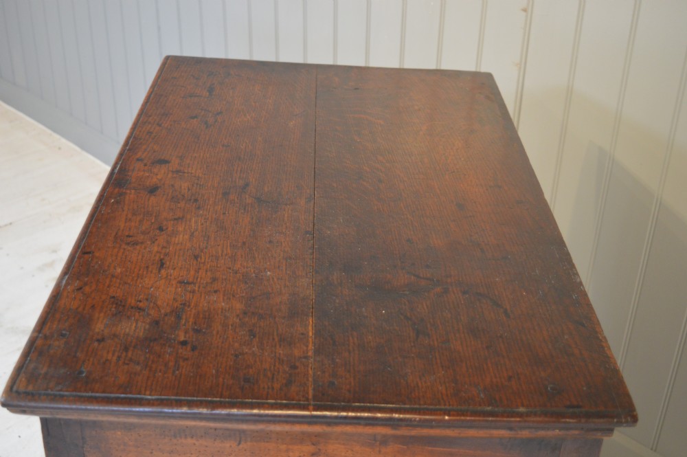 A 17th-century walnut chest of drawers with four moulded drawer fronts, brass drop handles, brass keyhole escutcheons, and large turned bun feet. View V