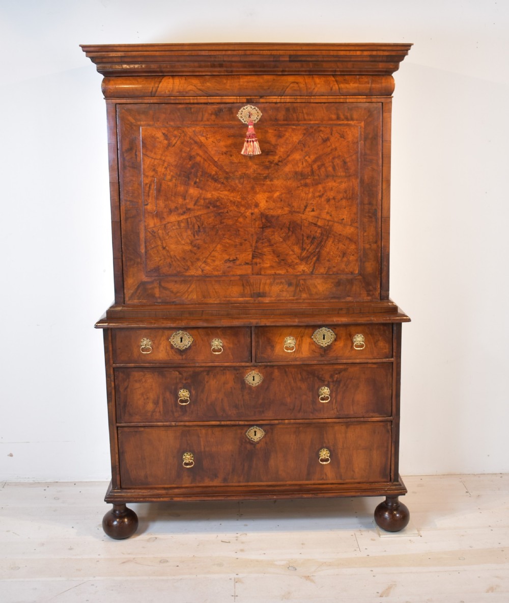 A Queen Anne walnut fall-front secretaire featuring a fitted interior with small drawers, green baize writing surface, brass drop handles, and turned bun feet. View II