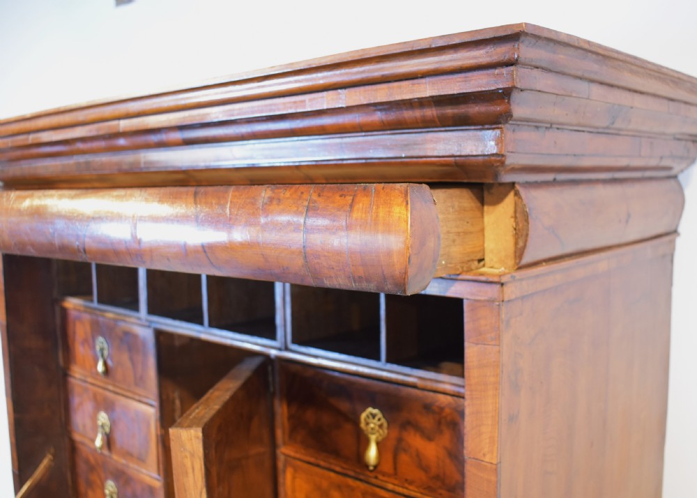 A Queen Anne walnut fall-front secretaire featuring a fitted interior with small drawers, green baize writing surface, brass drop handles, and turned bun feet. View IV