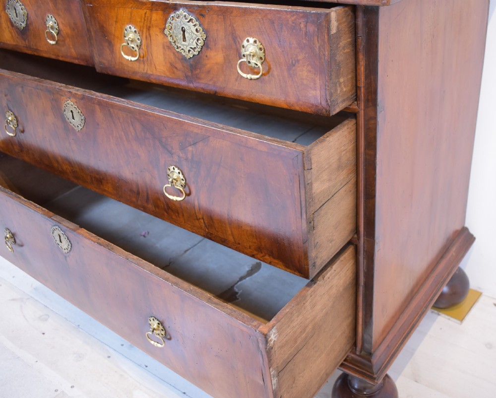A Queen Anne walnut fall-front secretaire featuring a fitted interior with small drawers, green baize writing surface, brass drop handles, and turned bun feet. View VI