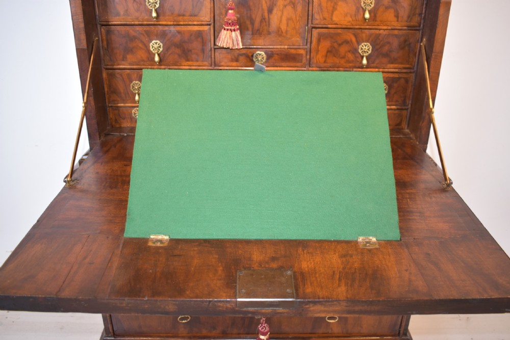 A Queen Anne walnut fall-front secretaire featuring a fitted interior with small drawers, green baize writing surface, brass drop handles, and turned bun feet. View IX