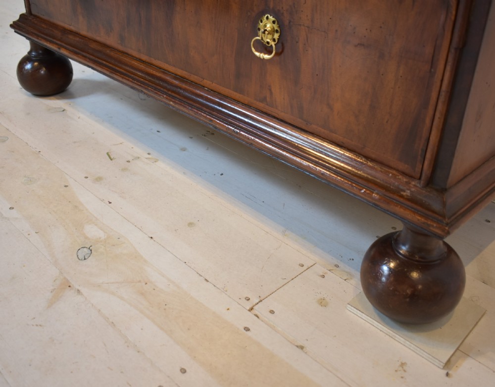 A Queen Anne walnut fall-front secretaire featuring a fitted interior with small drawers, green baize writing surface, brass drop handles, and turned bun feet. View X
