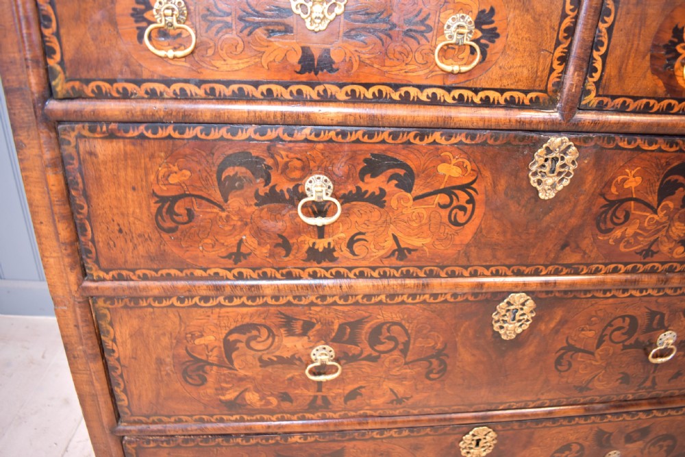 A 17th-century William and Mary walnut chest of drawers featuring intricate floral marquetry inlay, brass drop handles, decorative keyhole escutcheons, and bracket feet. View III