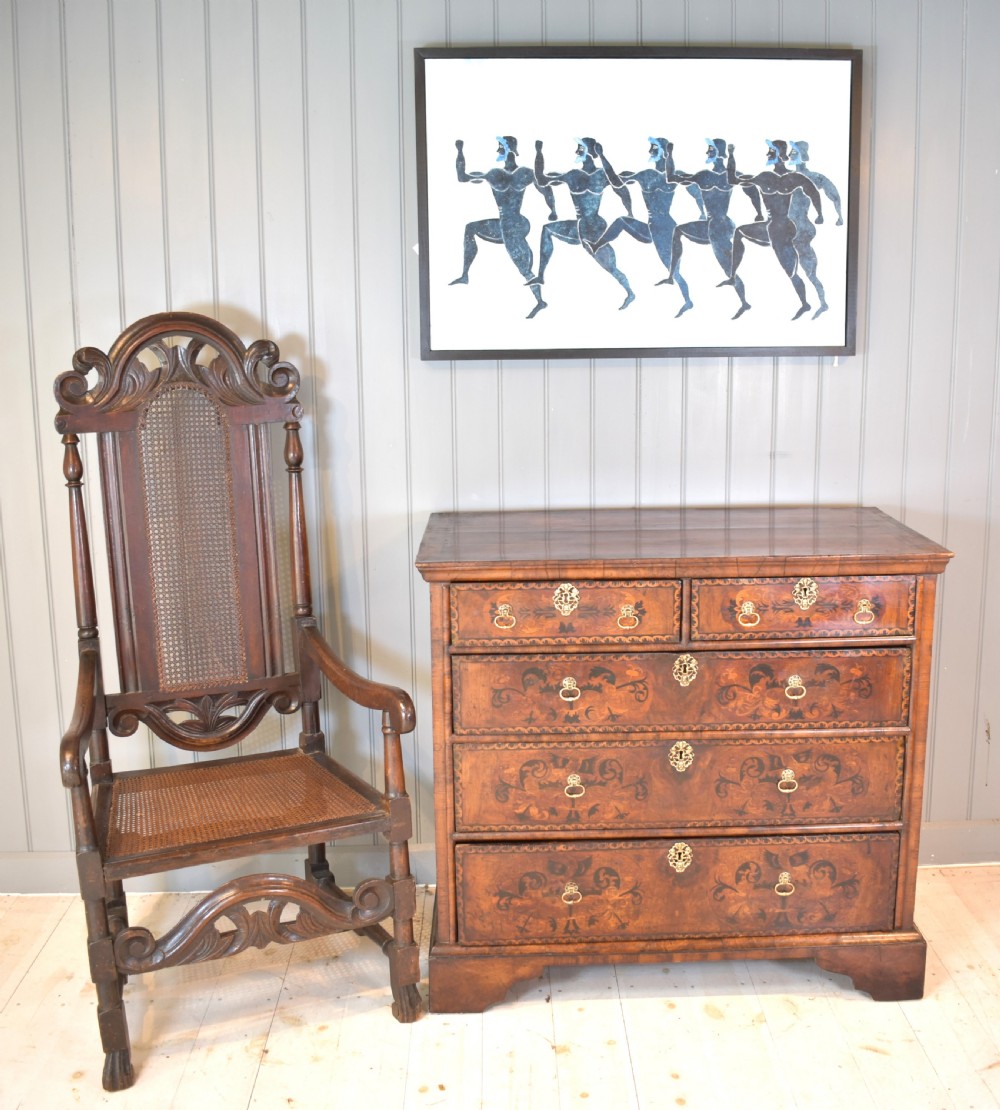 A 17th-century William and Mary walnut chest of drawers featuring intricate floral marquetry inlay, brass drop handles, decorative keyhole escutcheons, and bracket feet. View V