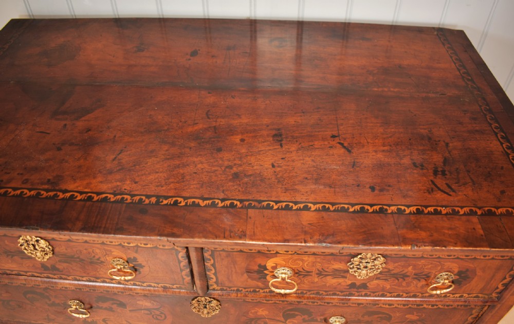 A 17th-century William and Mary walnut chest of drawers featuring intricate floral marquetry inlay, brass drop handles, decorative keyhole escutcheons, and bracket feet. View VII