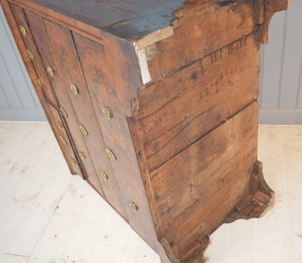 A 17th-century William and Mary walnut chest of drawers featuring intricate floral marquetry inlay, brass drop handles, decorative keyhole escutcheons, and bracket feet. View IX