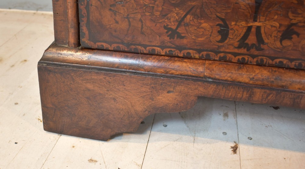 A 17th-century William and Mary walnut chest of drawers featuring intricate floral marquetry inlay, brass drop handles, decorative keyhole escutcheons, and bracket feet. View X