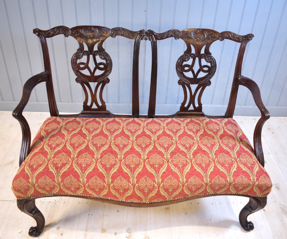 An 18th-century mahogany double-chair-back settee featuring pierced carved back splats, red patterned fabric upholstery, cabriole front legs, and curved armrests. View III
