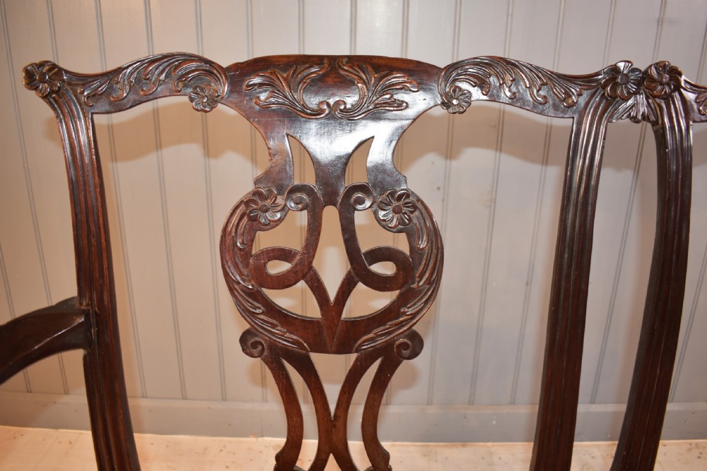 An 18th-century mahogany double-chair-back settee featuring pierced carved back splats, red patterned fabric upholstery, cabriole front legs, and curved armrests. View VIII