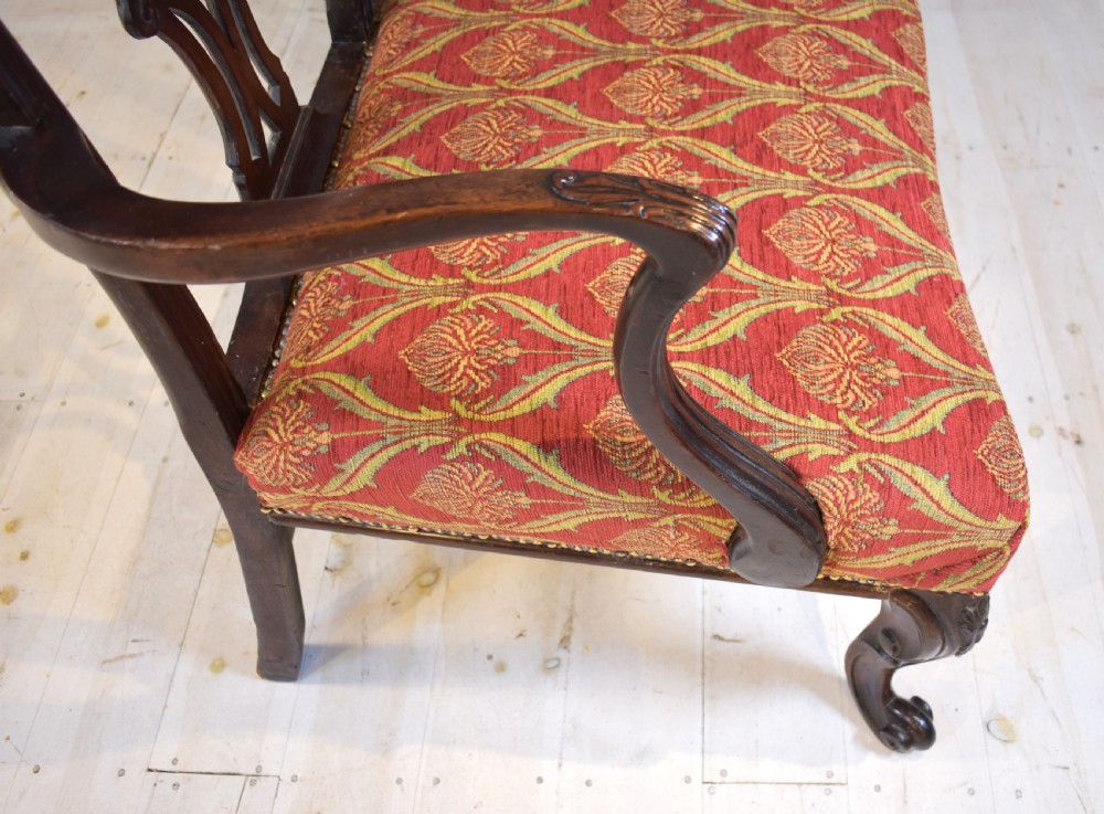 An 18th-century mahogany double-chair-back settee featuring pierced carved back splats, red patterned fabric upholstery, cabriole front legs, and curved armrests. View IX