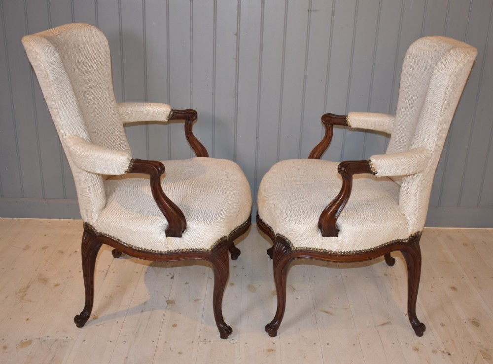 A pair of French Hepplewhite style armchairs upholstered in textured cream linen with carved dark mahogany frames and brass stud detailing. View IV