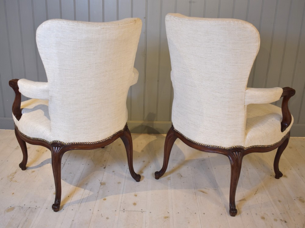 A pair of French Hepplewhite style armchairs upholstered in textured cream linen with carved dark mahogany frames and brass stud detailing. View V