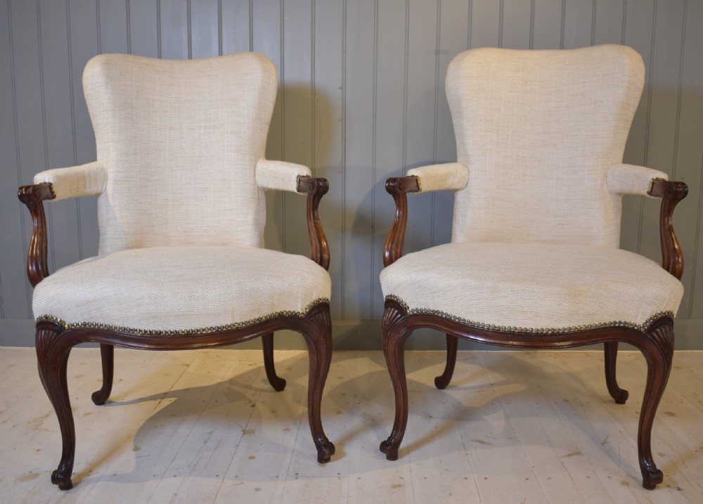A pair of French Hepplewhite style armchairs upholstered in textured cream linen with carved dark mahogany frames and brass stud detailing. View X
