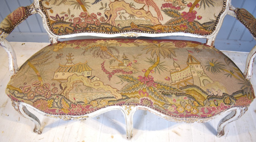 A French Louis XV style painted wooden settee with serpentine rails, cabriole legs, and woven tapestry upholstery featuring birds and palm trees. View V