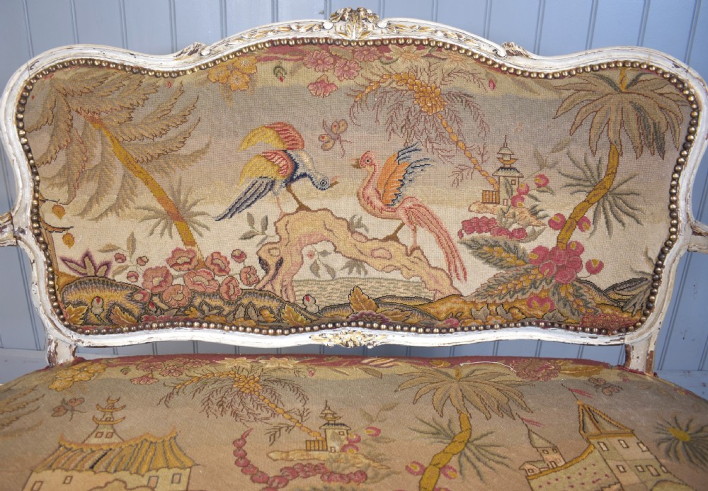 A French Louis XV style painted wooden settee with serpentine rails, cabriole legs, and woven tapestry upholstery featuring birds and palm trees. View VI